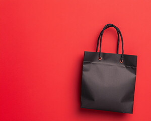 A black shopping bag is on a red background