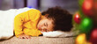 © Prostock-studio - Adorable african child sleeping on Christmas Eve on floor, close up