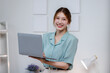 © David - Shot of beautiful smiling asian woman holding a laptop posing in front of camera on office background