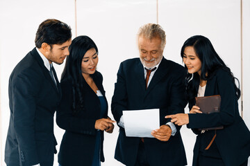 Wall Mural - Senior caucasian manager working in office with assistance of young Asian business people and translator in meeting. Corporate international business and secretary language translation concept. uds