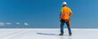 © Natalia - A roofer worker applying a reflective roof coating on a flat commercial roof to improve energy efficiency, reflective coating roofer, energy-efficient roofing
