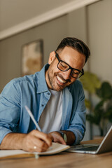 Portrait of handsome Caucasian man looking at laptop, working online from his home