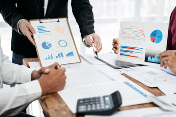 Fototapete - Three people are sitting at a table with papers and graphs in front of them
