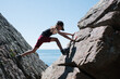 © Cavan Images - girl climbing rocks at the beach in Skåne in Sweden