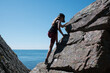 © Cavan Images - girl climbing the coastline rocks in Skåne Sweden in summer