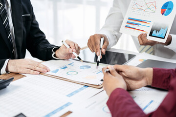 Fototapete - Three people are sitting at a table with papers and graphs in front of them