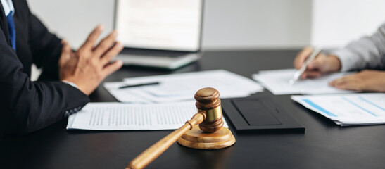 Wall Mural - Two people are sitting at a table with a gavel and papers in front of them