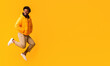 © Prostock-studio - Joyful afro guy in winter jacket jumping in the air over orange background