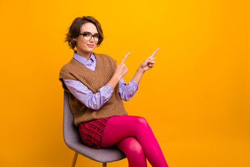 Poster - Photo portrait of attractive young woman sit chair point empty space dressed retro office clothes isolated on yellow color background