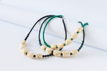 Straw and green bead necklace on a white background. Green and black beaded. 