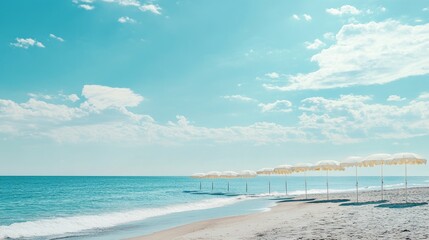 A line of sun umbrellas along the beach, with the endless ocean stretching out to meet the horizon on a bright summer day.