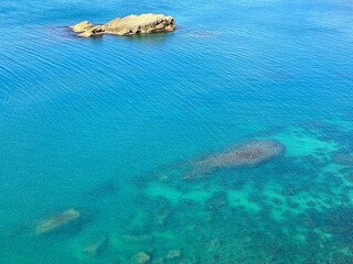 Wall Mural - Azure blue clear sea waters and rock aerial view. 