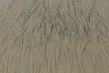 Closeup of abstract patterns on beach made by water. Background texture.