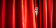 © ArtSav - Circus actor in makeup peeks out from behind a red curtain, before a performance, copyspace