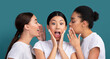 © Prostock-studio - Secret. Three Girls Friends Gossiping Sharing Rumors Standing In Studio On Turquoise Background. Panorama