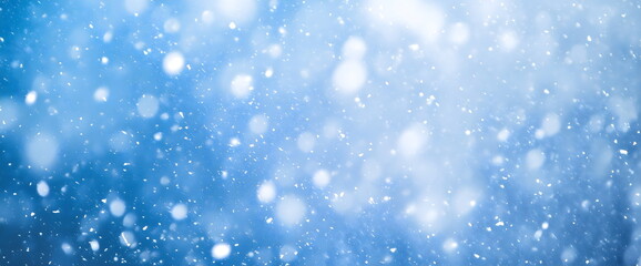 Magical winter snowfall scene with bokeh lights. Ethereal blue background for seasonal designs and holiday greetings