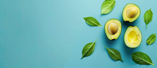 Fresh ripe avocado halves along with a leaf on a blue background ideal for copy space image