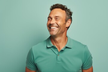 Canvas Print - Portrait of a happy man in his 40s wearing a breathable golf polo in soft teal background