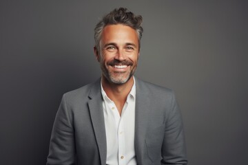 Poster - Portrait of a smiling man in his 40s dressed in a stylish blazer in front of soft gray background