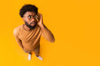 © Prostock-studio - Top view of african american shocked man wearing glasses, touching his head, full body over orange background