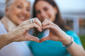 Elderly Woman and Caregiver Forming Heart Shape with Hands