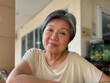 Happy asian Thai elder woman, mother sitting on wooden chair at home, taking selfie smiling to camera, insurance family concept.