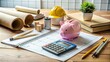 © Sirinporn - A neatly organized desk with a calculator, notebook, and Piggy Bank, surrounded by blueprints and construction tools,