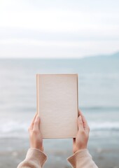 Sticker - A person holding a book sea outdoors nature.