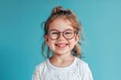 © Ilia K - Smiling young girl with glasses in a playful mood against a bright blue background during daytime