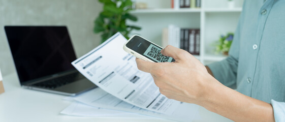 business man use phone to scan barcode or qr codes to pay credit card bill after receiving document 