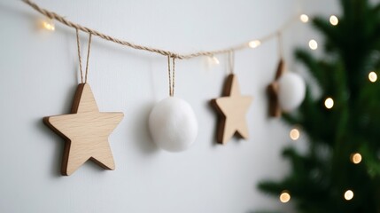 Wall Mural - Minimalist Christmas garland with white cotton balls and small wooden stars hanging on a white wall with fairy lights 