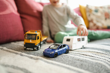 Cute boy playing with toy cars. Small child having fun with toys. Kid spending time in a cozy living room at home. Family leisure indoors.