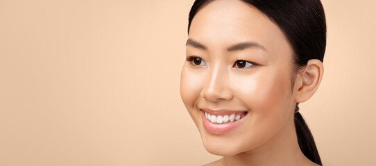 Wall Mural - Female Beauty. Closeup Portrait Of Happy Japanese Young Lady Smiling Looking Aside At Empty Space For Text, Advertising Products For Face Skin Care Over Light Gray Studio Background. Panorama