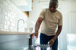 © Geber86 - Senior black man using dishwasher in modern kitchen