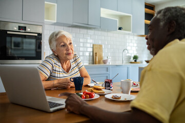 Wall Mural - Diverse senior couple eating breakfast together on the kitchen table