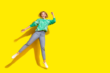 Poster - Full length photo of charming lucky woman wear green sweatshirt jumping high rising fist empty space isolated yellow color background