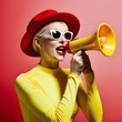 © SkyRebeL - Hear Me Roar: Stylish woman in a red hat and yellow, amplifies her voice with a megaphone against a vibrant pink backdrop.