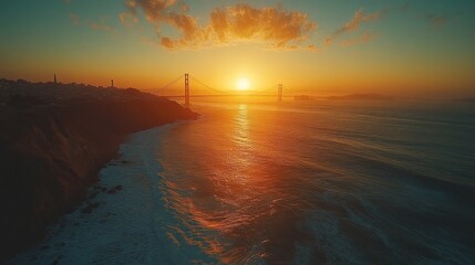 Sunset over a coastal landscape with a bridge in the distance.