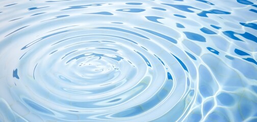 Circular ripples on clear blue water surface under sunlight