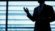 © Oksana Smyshliaeva - Silhouette of Businessman Gesturing with Confidence in Corporate Setting