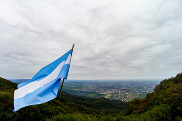 Argentine flag waves in the foreground with the city of San Miguel de Tucuman in the background