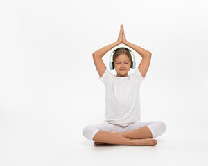 cute teen girl doing yoga, listening music with headphones, isolated white background.