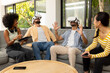 © wavebreak3 - Using VR headsets, diverse friends enjoying virtual reality experience together indoors