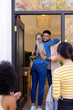 © wavebreak3 - Welcoming friends, man hugging woman at front door, others arriving