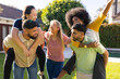© wavebreak3 - Friends having fun piggybacking and laughing together in backyard gathering