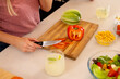 © wavebreak3 - Slicing red bell pepper on cutting board, person preparing fresh salad ingredients