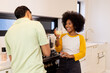 © wavebreak3 - Smiling woman holding drink, talking with friend in modern kitchen