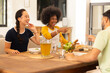 © wavebreak3 - Friends laughing and pointing while enjoying meal together at dining table