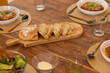 © wavebreak3 - Sliced loaf of bread on a wooden table, with bowls of pasta dinner