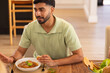 © wavebreak3 - Eating pasta and talking, man enjoying meal with diverse friends at dining table